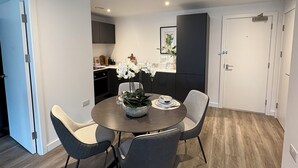 Een moderne eetruimte met een ronde tafel, vier stoelen en een vaas witte bloemen.