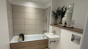 Een moderne badkamer met een douchecabine van glas, een houten wastafelmeubel, een wastafel en een toilet.