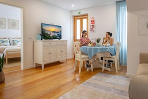 A hotel room with a bed, a dining table with chairs, a television, and a view of the sunset. - Casa de Sao Tiago 2 – Funchal (Funchal)