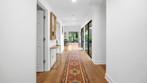 A hallway with a wooden floor, white walls, and a patterned rug. - Sea Pines Retreat: Private Deck & Plunge Pool! (Hilton Head Island)