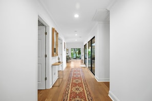 A hallway with a wooden floor, white walls, and a patterned rug. - Sea Pines Retreat: Private Deck & Plunge Pool! (Hilton Head Island)