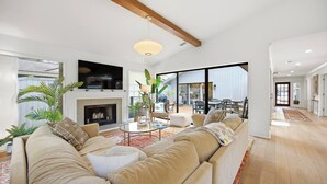 A modern living room with a fireplace, a large sofa, and a television. - Sea Pines Retreat: Private Deck & Plunge Pool! (Hilton Head Island)