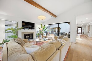 A modern living room with a fireplace, a large sofa, and a television. - Sea Pines Retreat: Private Deck & Plunge Pool! (Hilton Head Island)