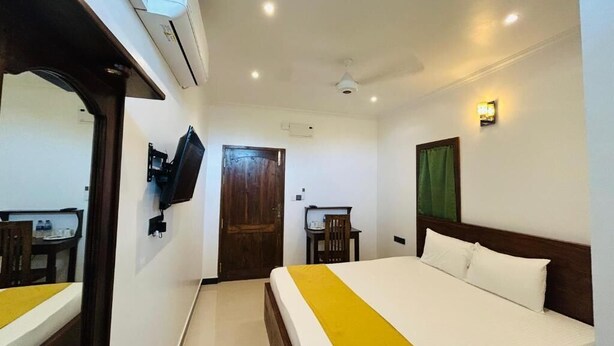 Une chambre d’hôtel équipée d’un lit, d’un bureau, d’une chaise, d’un climatiseur et d’un téléviseur.