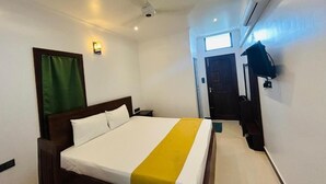 Une chambre d’hôtel équipée d’un lit, d’un ventilateur de plafond, d’un appareil de climatisation, d’une fenêtre et d’une porte.