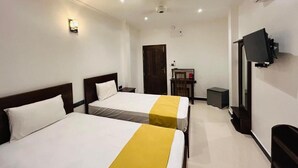Une chambre d’hôtel avec deux lits, une télévision, un bureau et une porte.