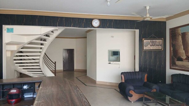 A living room with a spiral staircase, a ceiling fan, a clock, a television, and a framed picture on the wall.