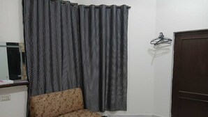 A room with a sofa, a small table, a door, and a curtain.