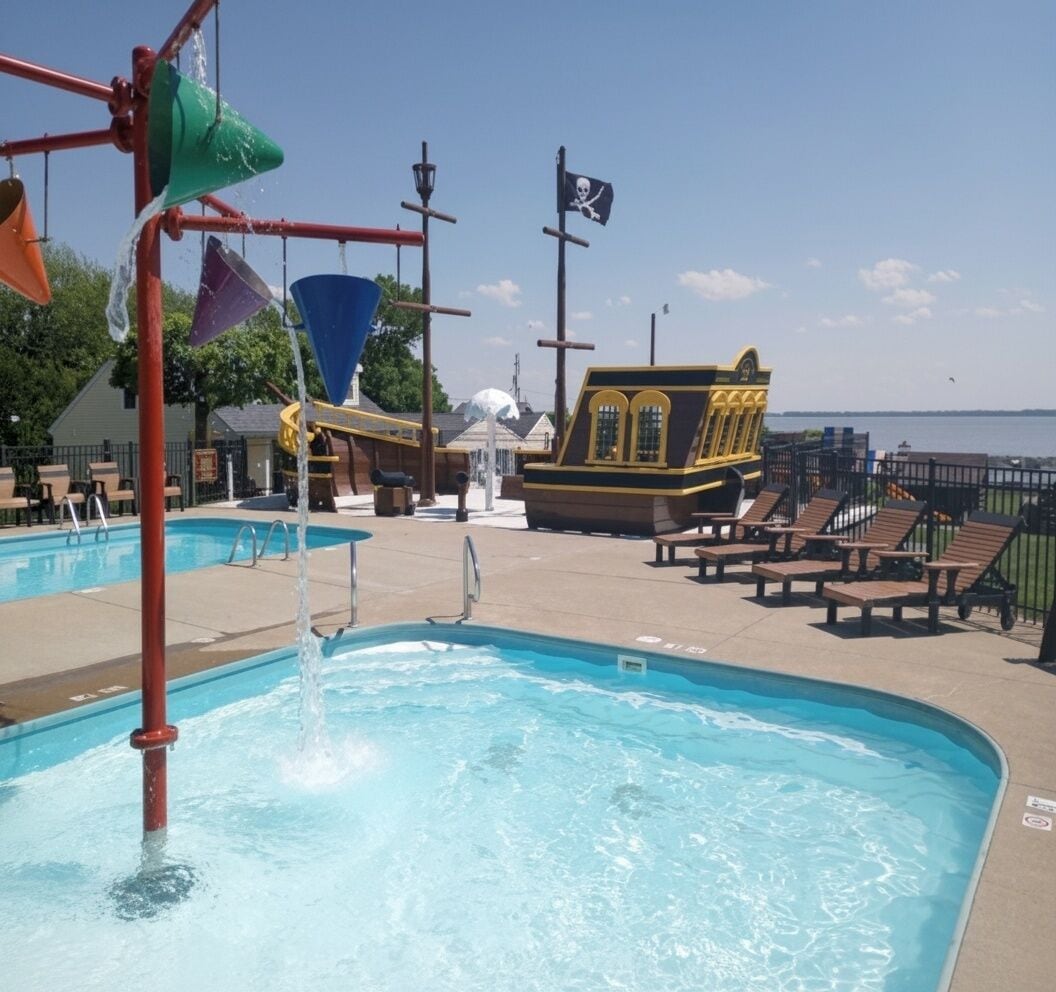 A swimming pool with water features, a pirate-themed building, and lounge chairs.