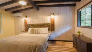A bedroom with a wooden headboard, a bed with white bedding, two wall-mounted lights, a window, and a small plant on a cabinet. - Unit 7 - Slide Rock Lodge (Sedona)