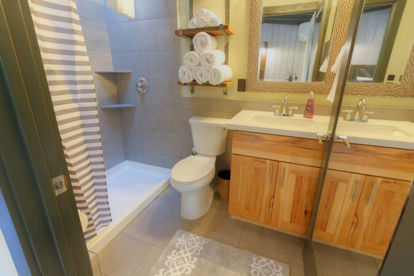 Une salle de bain équipée d’une douche, de toilettes, de meubles en bois, d’un lavabo et d’un miroir.