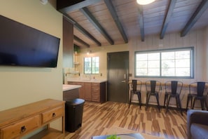 A kitchen with wooden cabinets, a sink, and a window. There are chairs and a table in the dining area. - Unit 10 - Slide Rock Lodge (Sedona)