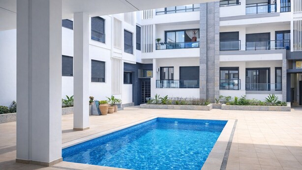 Un edificio moderno con piscina central, varios balcones y plantas en macetas.