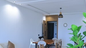 Una sala de estar moderna con un sofá, una mesa de comedor con sillas, una mesa auxiliar y un tapete estampado.