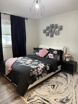 A bedroom with a bed, a nightstand, a wall art piece, and a window with curtains. - Luxury Modern Home in Calgary (Calgary)