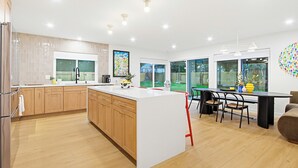 Una cocina moderna con armarios de madera, una isla central y un comedor con sillas.