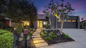 Una casa moderna con un jardín cuidado, un camino que lleva a la entrada y un garaje.