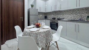 Una cocina moderna con armarios blancos, salpicadero de azulejos y una zona de comedor con una mesa preparada para cuatro.