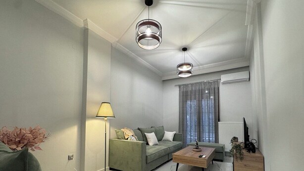 Una sala de estar moderna con sofá, mesa de centro, lámpara y lámparas colgantes.