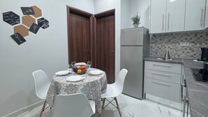 Una cocina moderna con armarios blancos, un refrigerador y un comedor con una mesa dispuesta para cuatro personas.