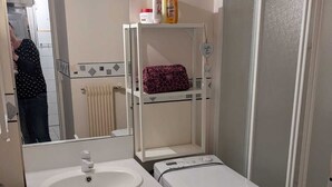 Ein Badezimmer mit Waschbecken, Spiegel, Handtuchhalter und Duschkabine.