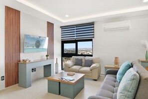 A modern living room with a fireplace, a sofa, a coffee table, and a large window with blinds. - Malecón | Amplio | Torre de Lujo (Mazatlán)