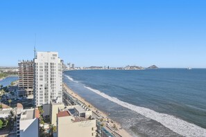 Ein Hotel an der Küste mit mehreren Etagen, Blick auf den Strand und blauem Himmel.