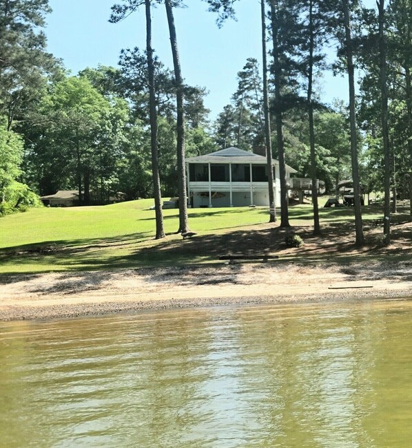 A lakeside property with a covered pavilion, a grassy area, and a dock.