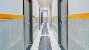 A long, narrow hallway with marble walls and doors, leading to rooms. - Premium Hotel Maharana Pratap (Ujjain)