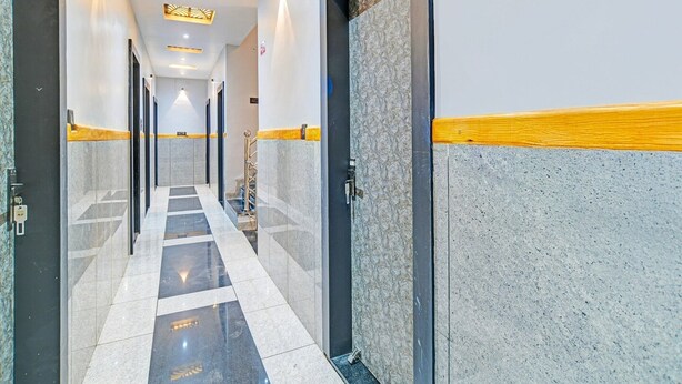 A hotel hallway with a tiled floor, doors with a stone finish, and recessed lighting. - Premium Hotel Maharana Pratap (Ujjain)