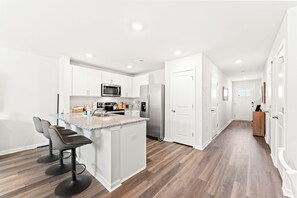 A modern kitchen with white cabinets, a granite countertop, and stainless steel appliances. - Modern 3BR Townhouse w/ Porch Near Beach & Golf - Surfside Beach (Surfside Beach)
