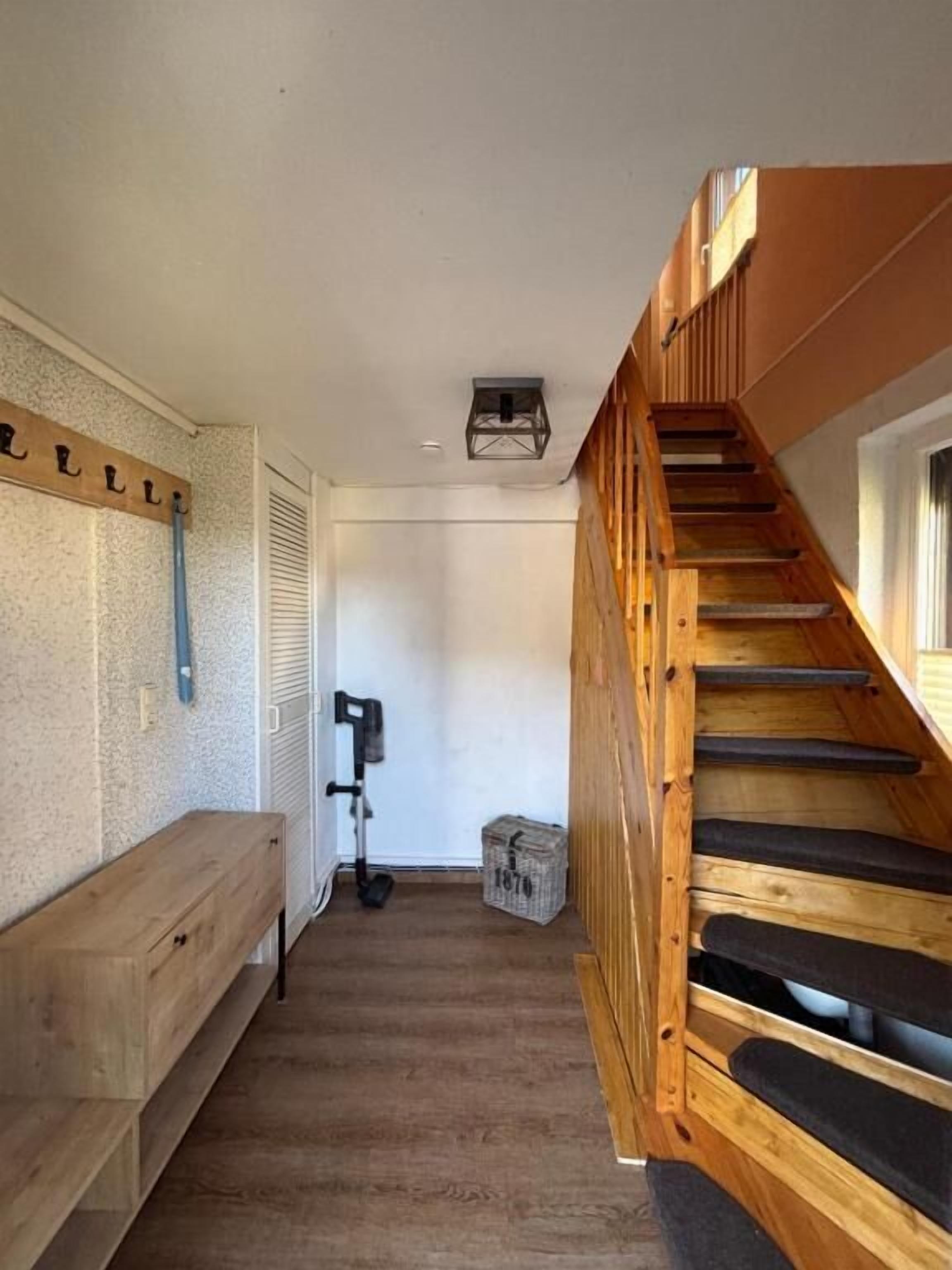 Un escalier menant à un niveau supérieur, un banc, un luminaire au plafond et un panneau fixé au mur.
