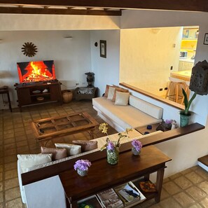 Una sala de estar con chimenea, un sofá, una mesa de centro y un comedor con barra.