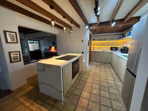 Una cocina moderna con una isla central, horno empotrado y suelo de baldosas de piedra.