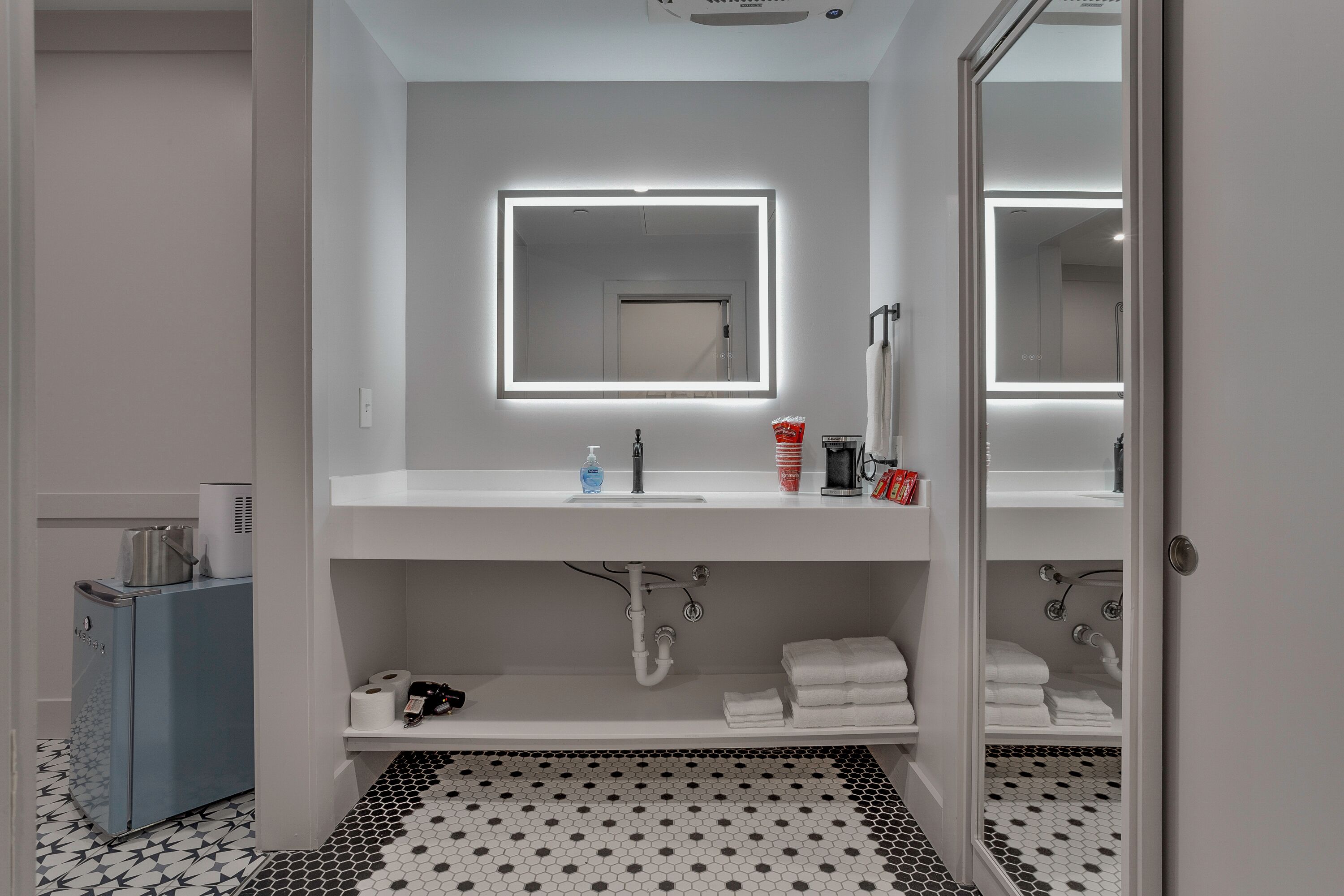 A modern bathroom with a white sink, a mirror with underlighting, a toilet, and a shower area.