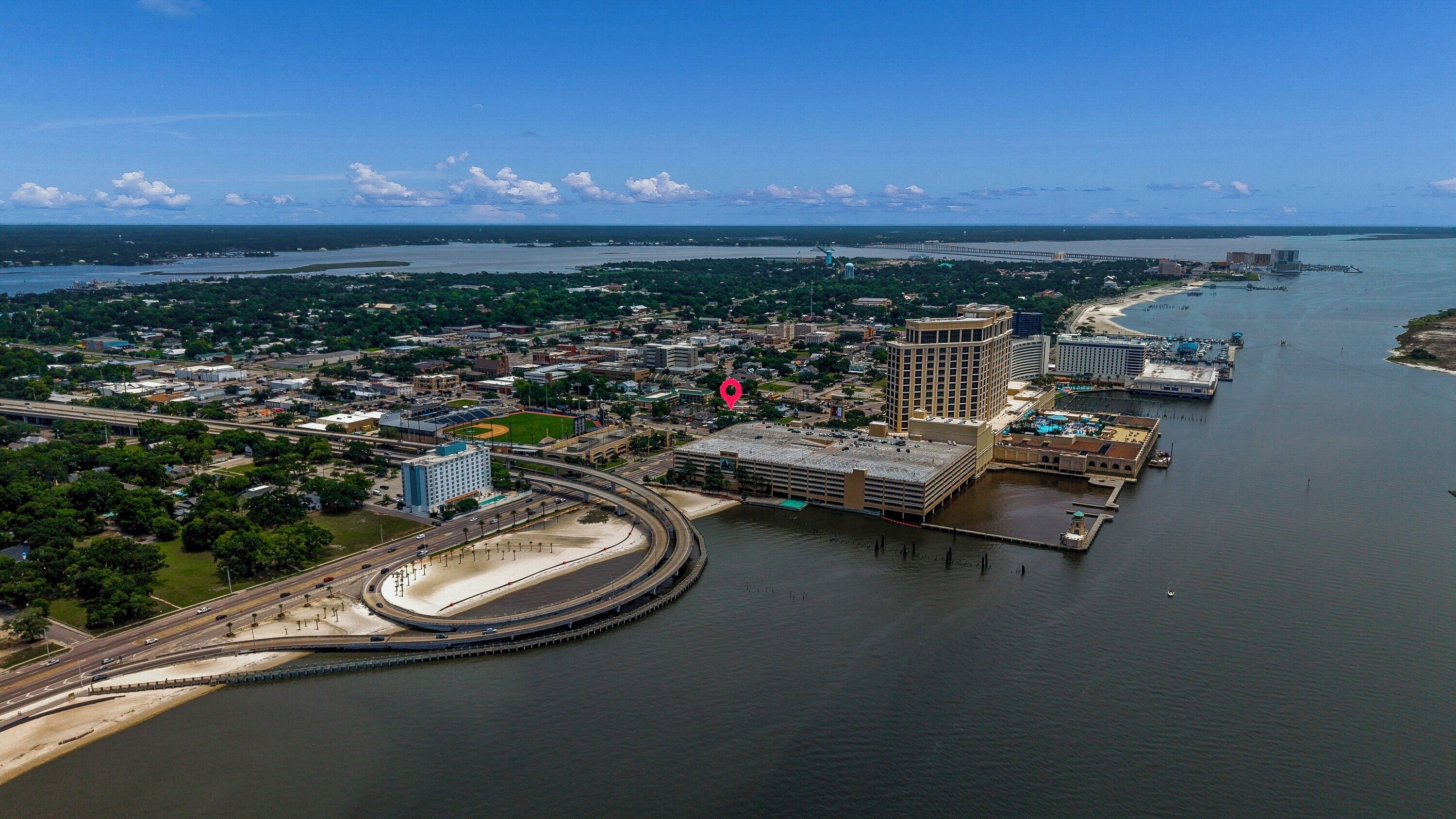 Vue aérienne d’une ville côtière avec un port de plaisance, un grand hôtel et un complexe sportif.