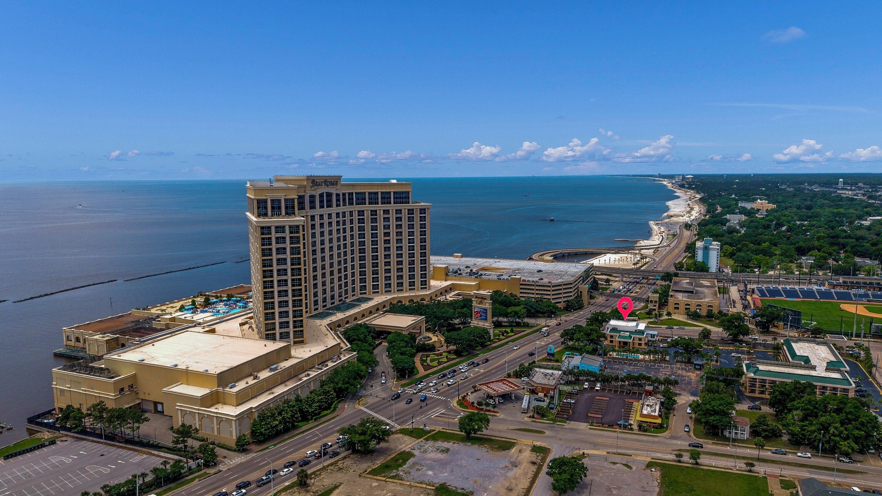 A high-rise hotel with a pool, adjacent to a beach and a baseball stadium.
