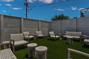 Un espace patio aménagé avec du mobilier d’extérieur et du gazon synthétique.