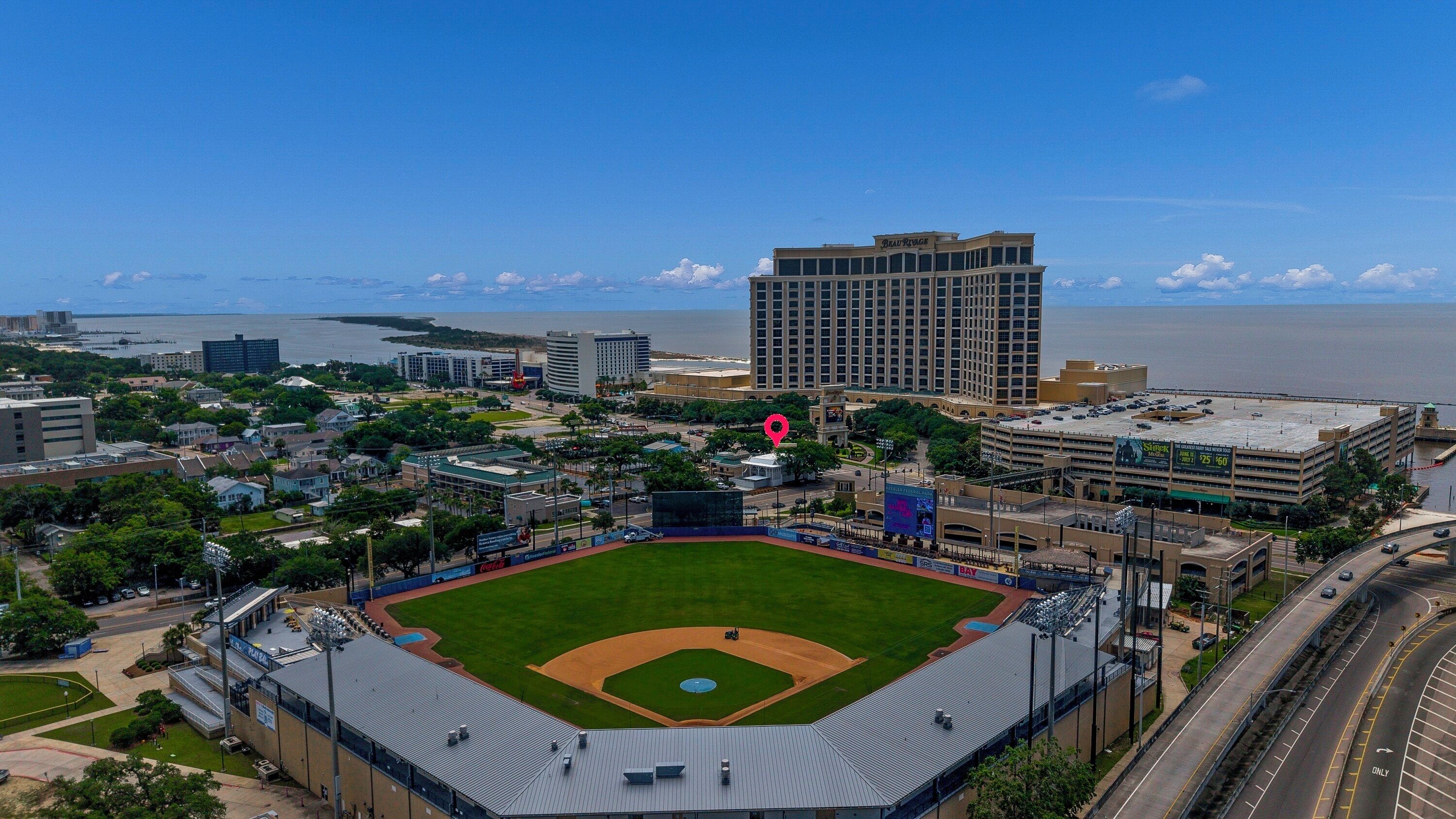 A baseball stadium with a large field, surrounding buildings, and a view of the water.