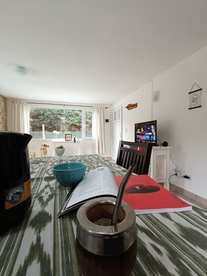 A living room with a large window, a television, a book, a bowl, and a large bottle.