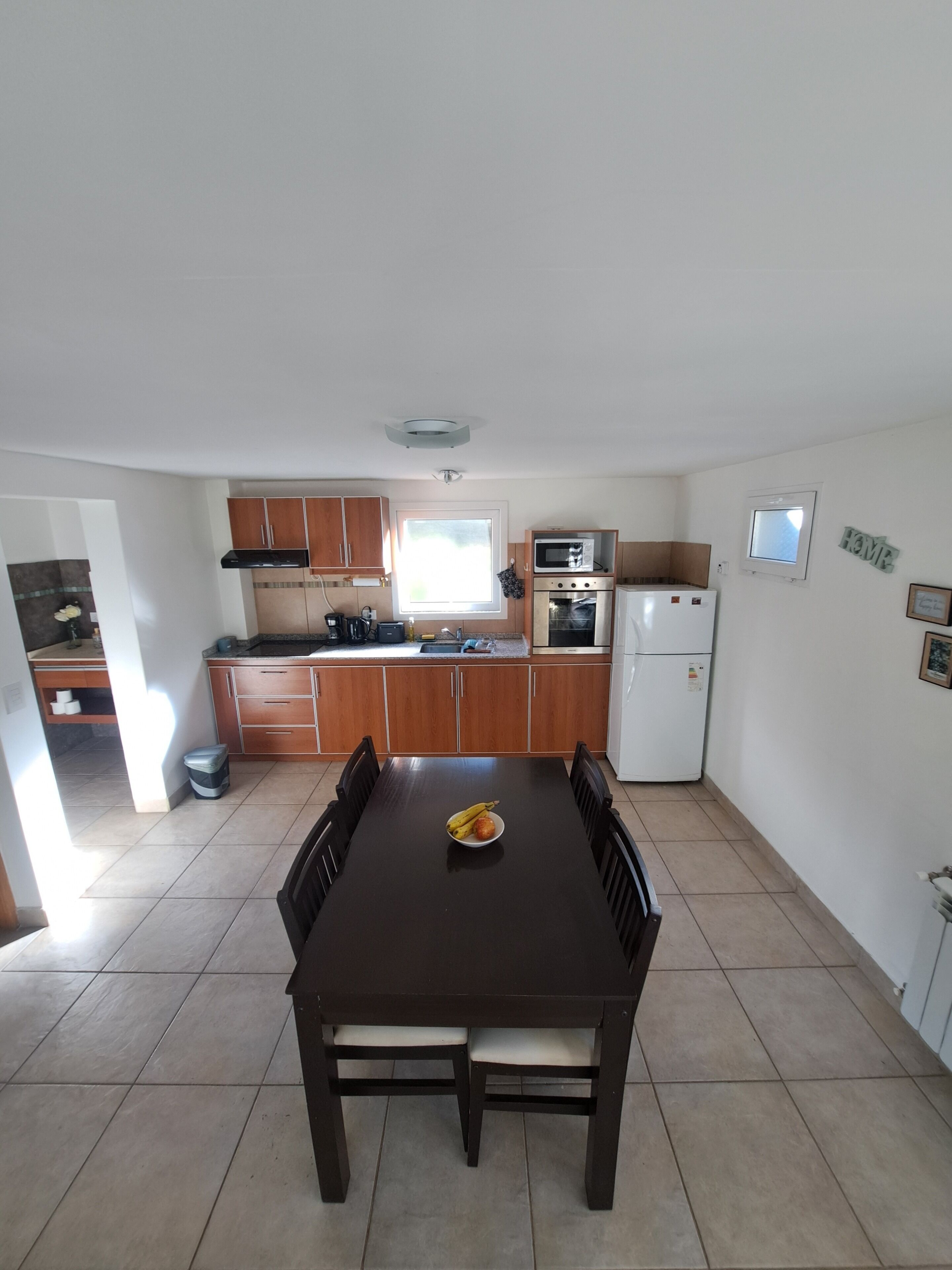 Una cocina compacta con armarios de madera, microondas, horno y refrigerador.