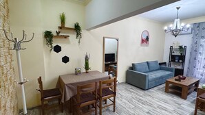 En stue med spisebord, stole, sofa, fjernsyn og en lysekrone.