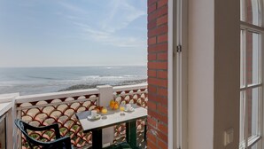 Uma varanda com mesa posta para o café da manhã, com vista para o oceano.