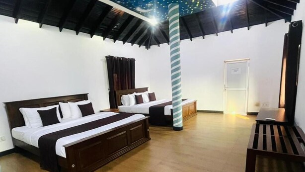 A hotel room with two beds, a wooden floor, a striped column, and a door.