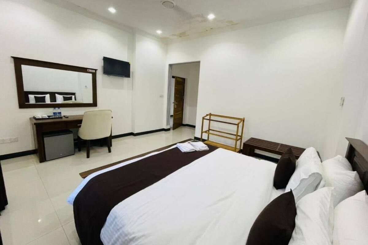 Hotellihuone, jossa on sänky, työpöytä, tuoli, televisio ja peili.