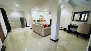 A spacious living area with a sofa, a dining table, and a refrigerator.