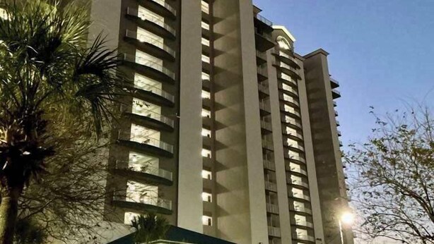 A multi-story hotel with a central atrium, parking garage, and palm trees. - Lakefront Condo 1 Mile to Disney w/ Pool, Hot Tub (Orlando)