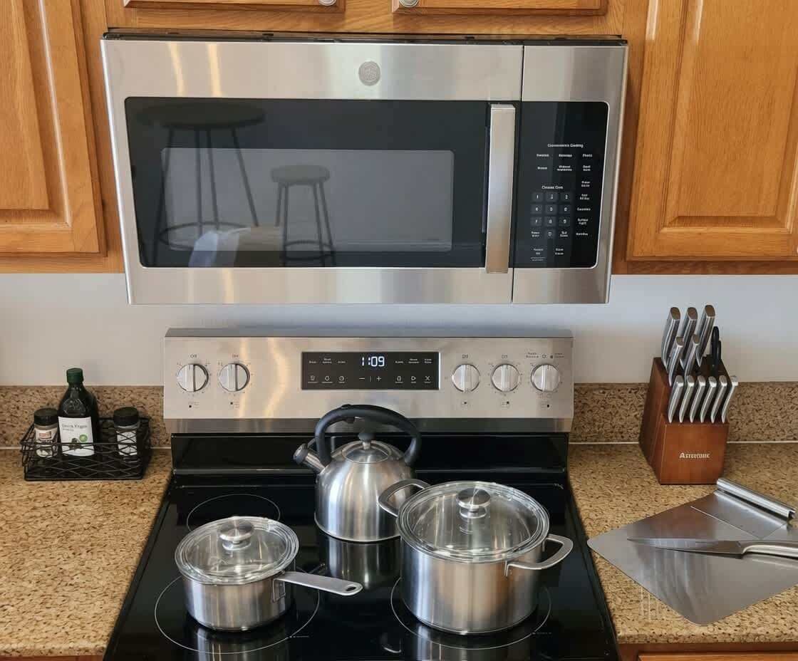 A kitchen with a stainless steel microwave, stove, and pots.