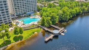 A hotel with a swimming pool surrounded by lush greenery and a dock extending into a body of water. - Lakefront Condo 1 Mile to Disney w/ Pool, Hot Tub (Orlando)
