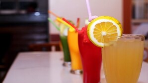 Una mesa con un vaso de una bebida amarilla adornada con una rodaja de limón y una pajita.